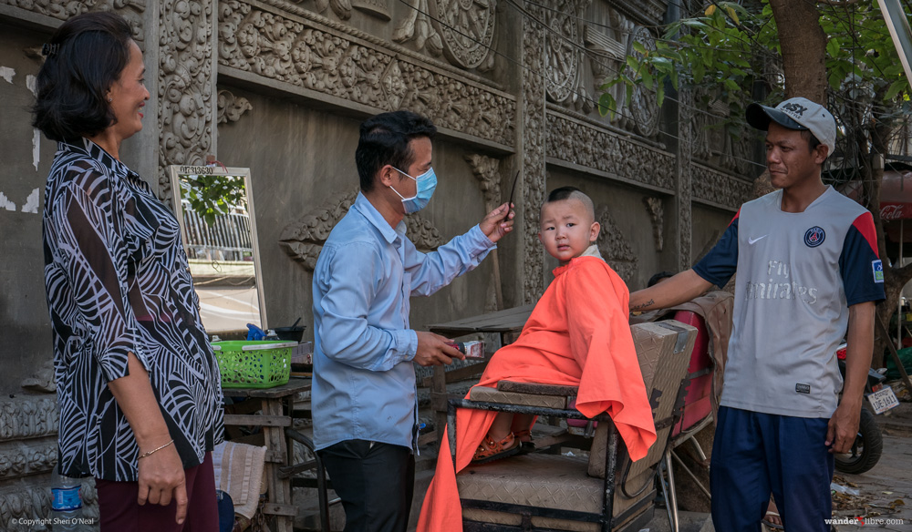 A roadside barber gives a young boy a mohawk for his first haircut in Phnom Penh, Cambodia.