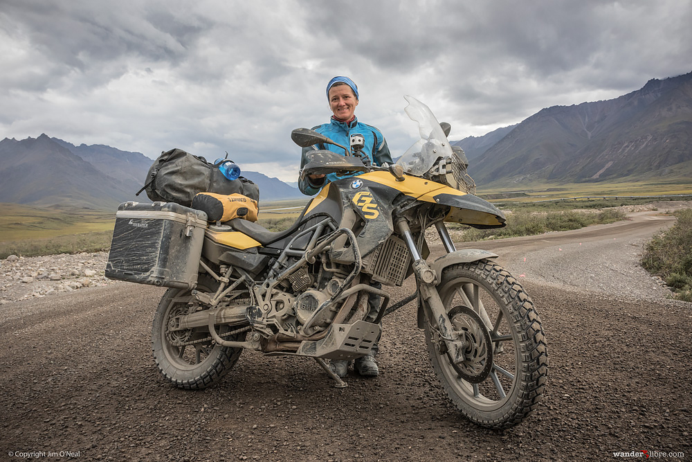 A portrait of Sheri and her motorcycle with the Brooks Range in the background, which was taken on Alaska's Dalton Highway near Deadhorse.