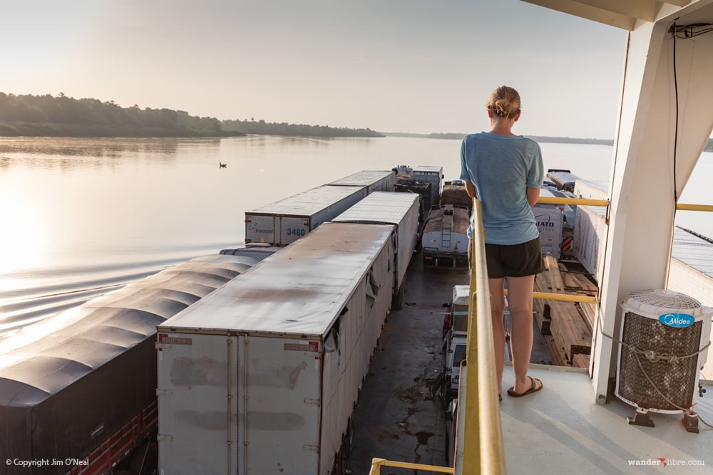 Sheri on a barge in the Amazon River looking out over cargo trucks